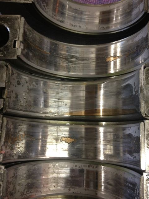 1965 Ford Fairlane - Close-up view of damaged engine bearings, indicating significant wear and potential failure.