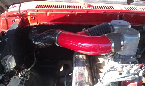 1978 Ford Bronco - Close-up of a vehicle's engine air intake system with red piping and dual air filters.