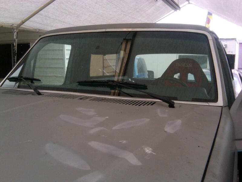 Front view of a truck's hood and windshield, with a red racing seat visible inside