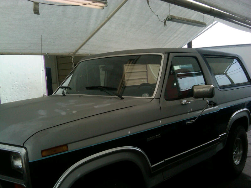 1986 Ford Bronco, two-tone gray and black paint, parked under a canopy