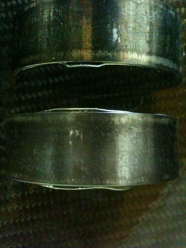 two engine bearings, one on top of the other, showing wear