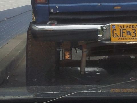 1990 Chevrolet Suburban - Rear view of a blue vehicle showing an Alaska license plate and chrome bumper.