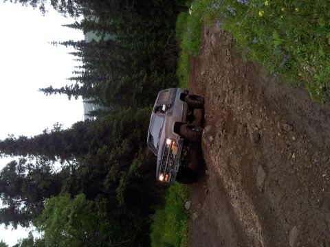 1990 Chevrolet Suburban - This 1990 Chevrolet Suburban navigates a challenging off-road trail surrounded by lush green trees.