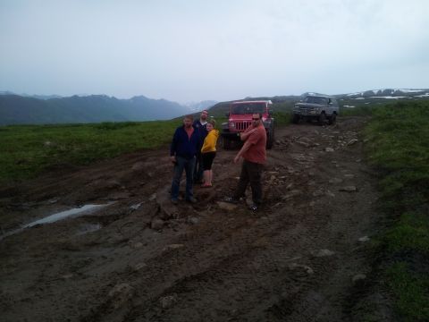 1990 Chevrolet Suburban - A group of people and their off-road vehicles navigate a challenging, muddy mountain trail.
