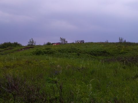 1990 Chevrolet Suburban - Two SUVs are visible on a hill under a cloudy sky.