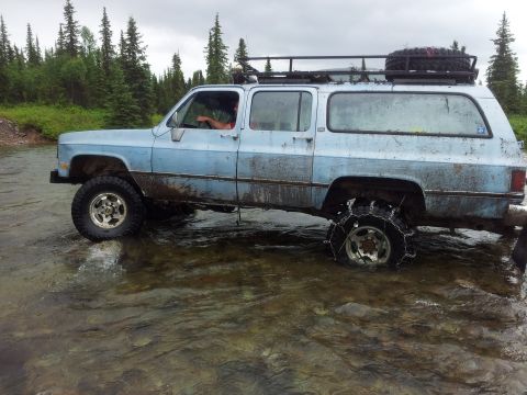 1990 Chevrolet Suburban - This 1990 Chevrolet Suburban is navigating a stream, equipped with tire chains for traction.