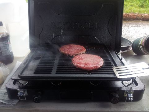 1990 Chevrolet Suburban - Burgers cooking on a portable grill outdoors.