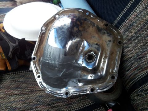 1990 Chevrolet Suburban - A differential cover with tape applied to its surface is shown, placed on a seat with other items nearby.