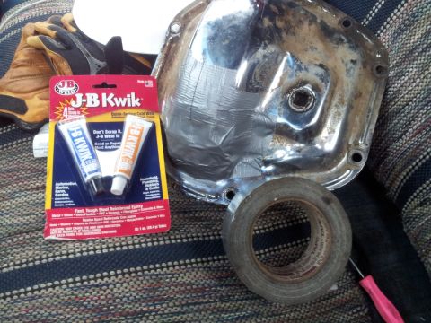 1990 Chevrolet Suburban - A chrome differential cover, JB Kwik adhesive, and tape are laid out, suggesting a repair or modification project.