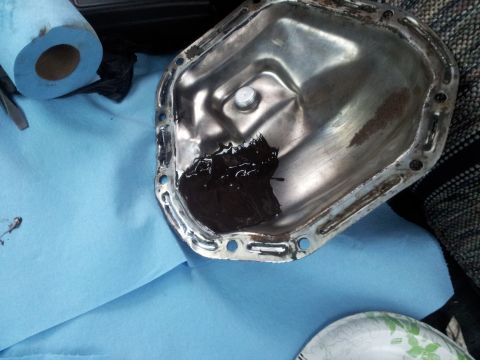 1990 Chevrolet Suburban - A removed oil pan gasket shows signs of old sealant and wear, with cleaning supplies in the background.