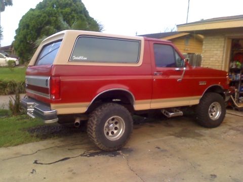 1990 Ford Bronco - This red and tan Ford Bronco has a lifted suspension and aftermarket wheels, suggesting it is not a 1990 model.