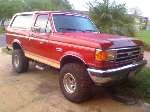 1990 Ford Bronco - This red 1990 Ford Bronco features tan side trim and an elevated suspension system.