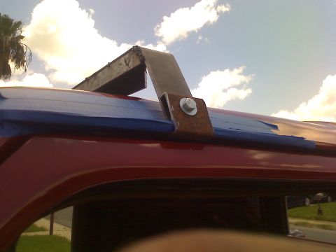 1990 Ford Bronco - Close-up of a custom roof rack being installed on a red vehicle, with blue painter's tape along the roofline.
