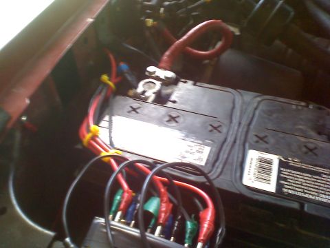 1990 Ford Bronco - Close-up of a car battery with various wires and test leads connected to its terminals.