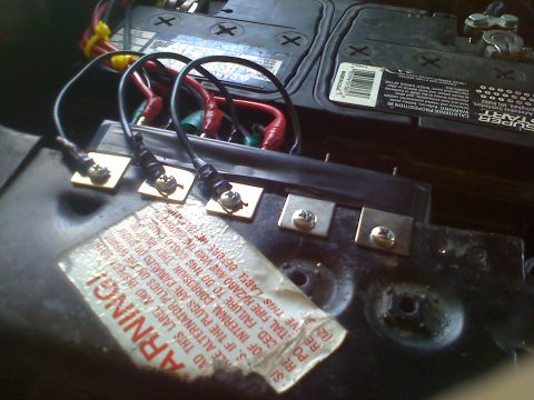 1990 Ford Bronco - Close-up of car battery terminals and wiring with a warning label.