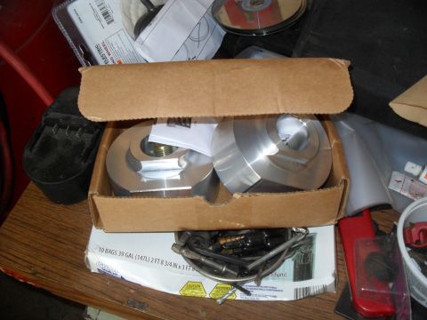 1990 Ford Bronco - Lift kit components are shown in a cardboard box, with other items scattered around.