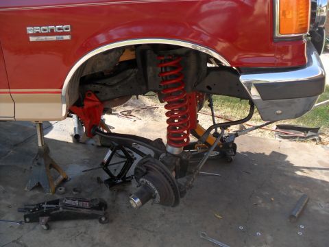 1990 Ford Bronco - Front suspension of a 1990 Ford Bronco is disassembled for repair, showing red lift springs.