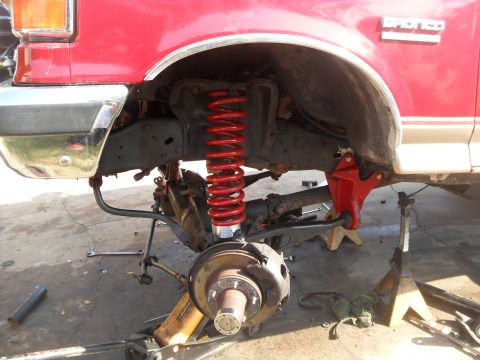 1990 Ford Bronco - The front suspension of a red 1990 Ford Bronco is shown with a lift kit installed.