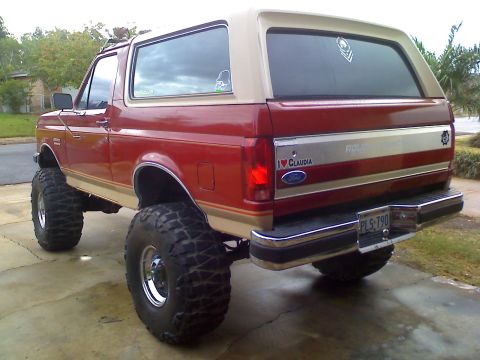 1990 Ford Bronco - This 1990 Ford Bronco is equipped with large off-road tires and has a two-tone red and tan paint scheme.