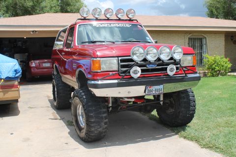 1990 Ford Bronco - This lifted Ford Bronco has a "Rough Country" sticker on the windshield and multiple Hella lights mounted on the front.