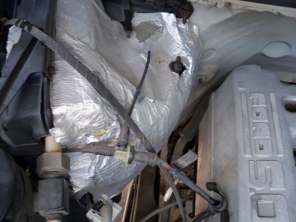 1995 Ford Bronco engine compartment with silver "Ford" branded valve cover and silver insulation