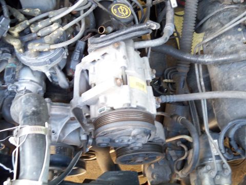 1995 Ford Bronco - Close-up view of a cluttered engine bay with many components visible.