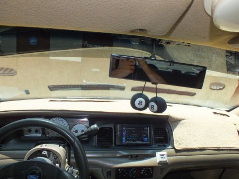 2003 Ford Crown Victoria - View across a tan Crown Victoria dashboard showing aftermarket head unit and rearview camera display.