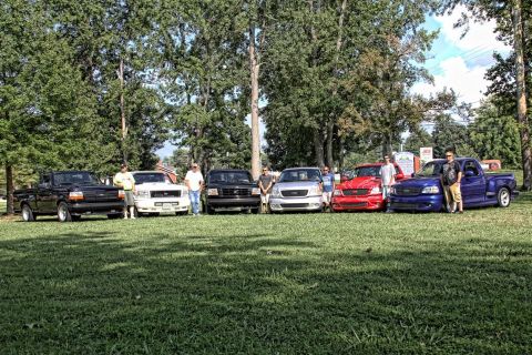 2007 Ford Mustang - A group of Ford F-150 SVT Lightning trucks are lined up on a grassy field, with people standing near them.