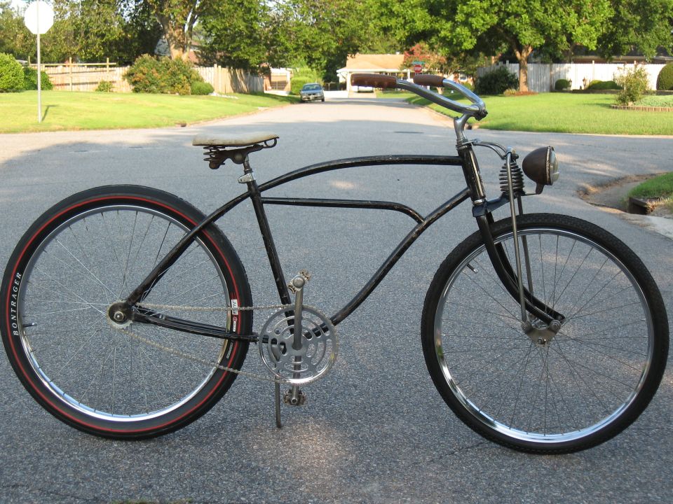 Black cruiser bicycle with red-striped tires and a headlight