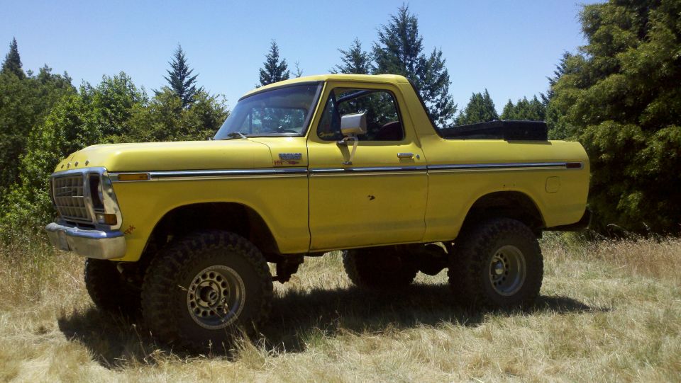 Yellow 1978 Ford Bronco with lifted suspension and off-road tires, side view