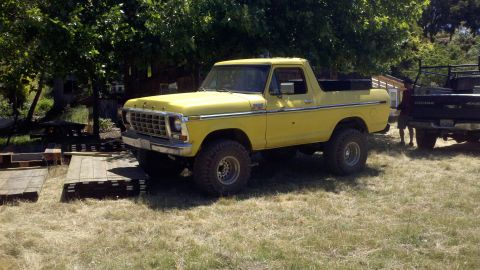 1978 Ford Bronco - 1978 Ford Bronco with off-road tires sits in a yard next to a Dodge pickup.