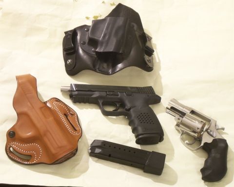 2000 Mercury Grand Marquis - A collection of firearms and their carrying holsters are displayed on a flat surface.