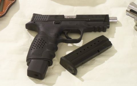 2000 Mercury Grand Marquis - A black semi-automatic pistol with an extended magazine sits next to a detached magazine, with other firearm components visible.
