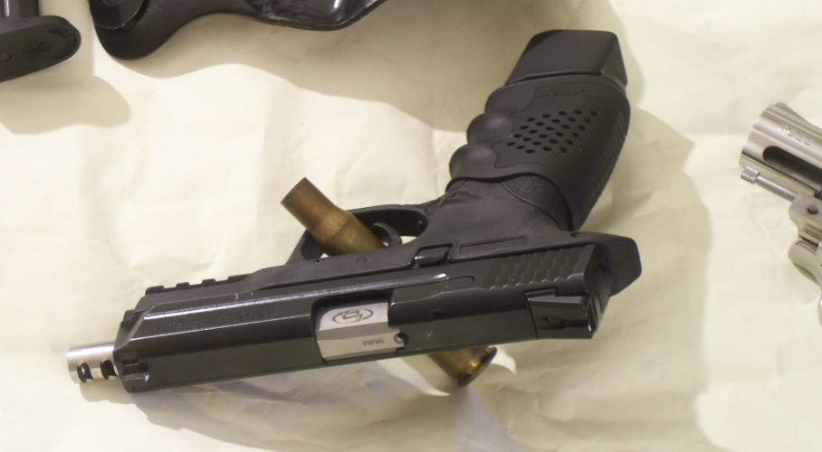 Black pistol with bullet casing, part of a revolver visible