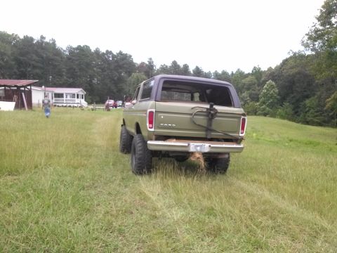 1979 Ford Bronco - The rear view of an olive green Ford Bronco shows its spare tire mount and lifted suspension.