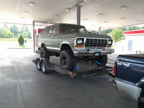 1979 Ford Bronco - A lifted green Ford Bronco is being transported on a trailer.