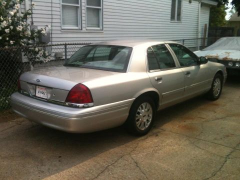 2004 Ford Crown Victoria - A silver 2004 Ford Crown Victoria is parked on a concrete driveway in front of a house.