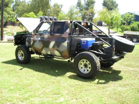 1987 Suzuki Samurai - This heavily modified pickup truck features a camouflage paint job and off-road modifications, including a roll cage and external storage.