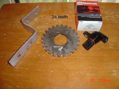 1997 Ford Ranger - A Motorcraft box, crankshaft position sensor, tone ring, and mounting bracket are displayed on a wooden surface.