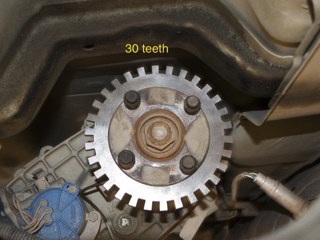 Close-up of a toothed metal wheel with 30 teeth, bolted to a vehicle's drivetrain component
