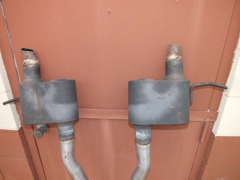 2003 Ford Crown Victoria - Pair of mufflers with crossover pipe shown against a red metal door.