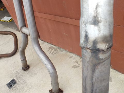 2003 Ford Crown Victoria - Detail of a heat-discolored exhaust weld with flanged pipe ends nearby.