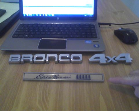 1994 Ford Bronco - Emblems for a Ford Bronco and Eddie Bauer trim are laid out on a table next to a laptop.