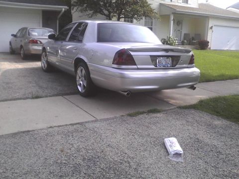 2003 Ford Crown Victoria - Rear view of a silver 2003 Ford Crown Victoria with tinted taillights and aftermarket wheels.