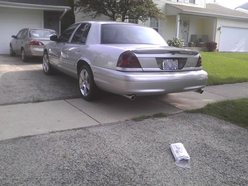 Silver Ford Crown Victoria sedan parked in a residential driveway