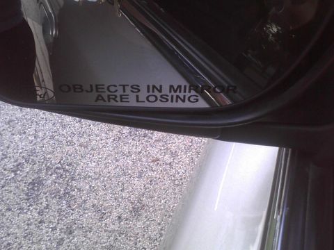 2003 Ford Crown Victoria - A side mirror displays the humorous text 'Objects in mirror are losing'.