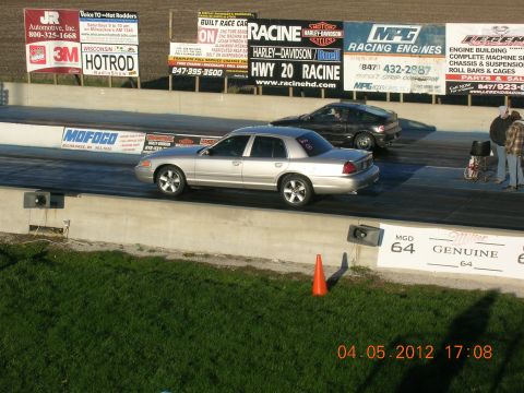 2003 Ford Crown Victoria - A silver Ford Crown Victoria competes in a drag race, with another car alongside it on the track.