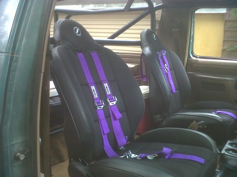 1990 Ford Bronco - Custom racing seats with purple harnesses and a roll cage are visible inside the vehicle's interior.