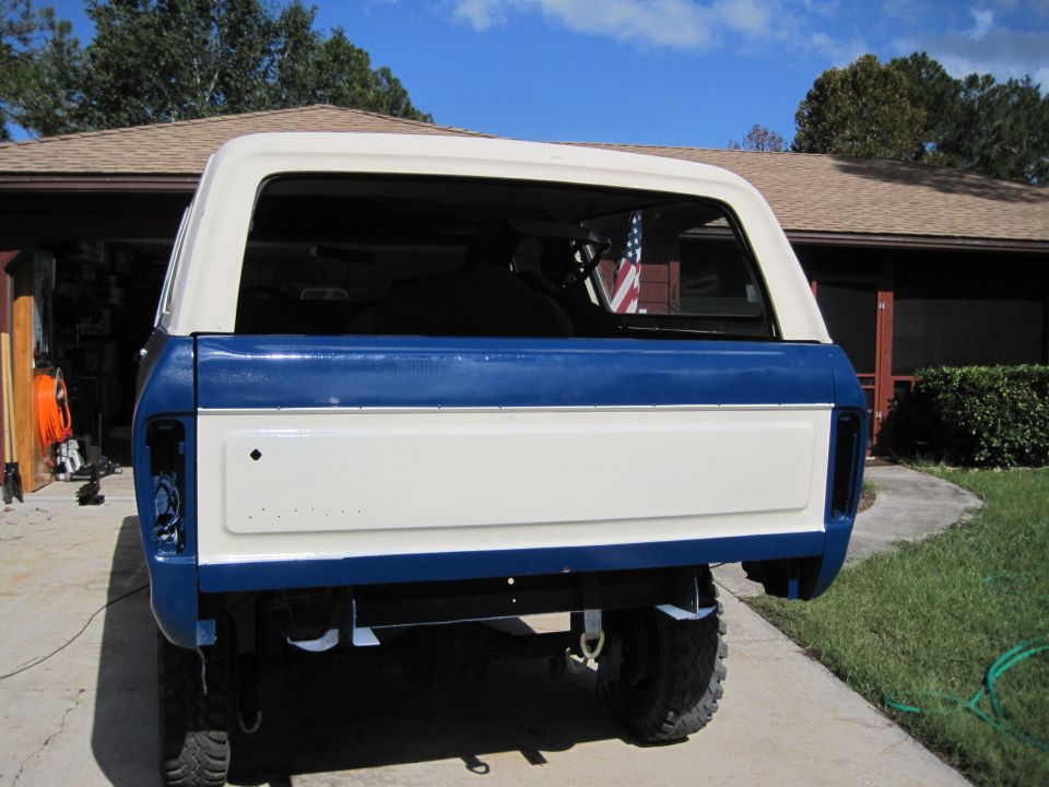 Rear view of lifted two-tone blue and white SUV with fresh paint, parked in driveway by garage