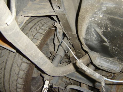 1987 Ford Mustang - Close-up of the undercarriage, focusing on the rear wheel assembly and exhaust system.